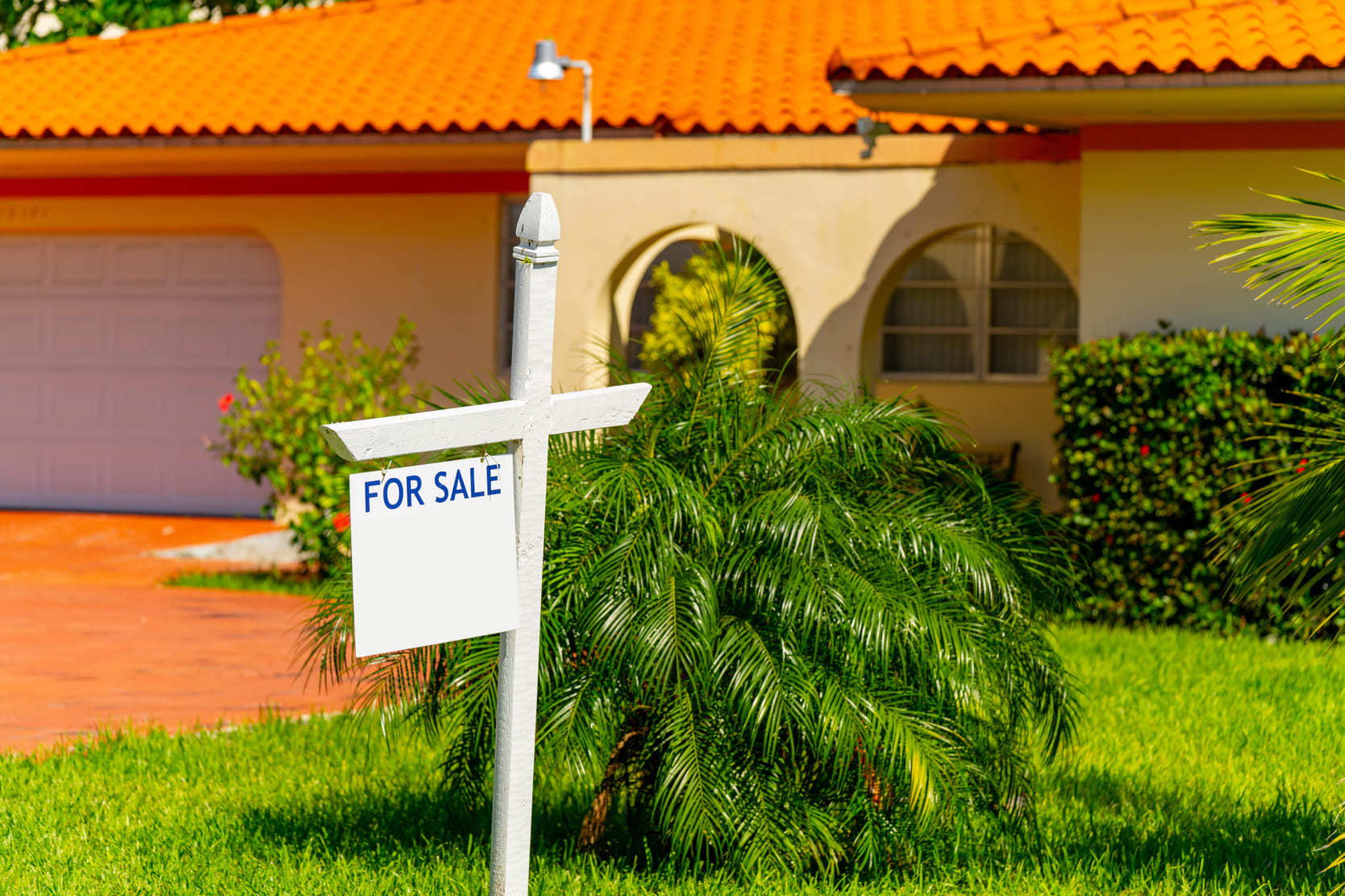 Home for sale in Florida with a for sale sign on the lawn.